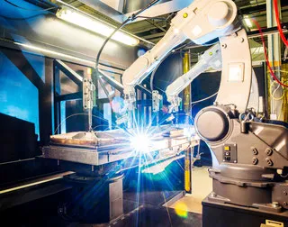 Robot industrial soldando con un arco brillante en la pieza